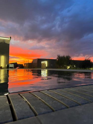 a pool of water with a building and the sunset at Agriturismo il Cappero b&b Marzamemi in Noto