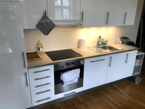 a kitchen with white cabinets and an oven and a sink at Fin og super sentral leilighet in Bergen