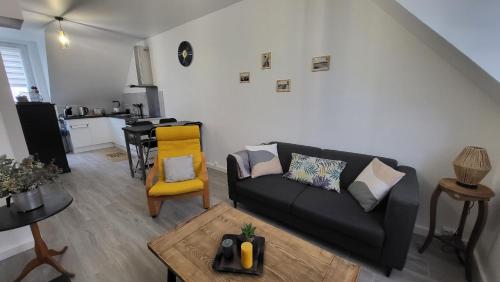 - un salon avec un canapé noir et un fauteuil jaune dans l'établissement Maison de ville avec garage, à Beaugency