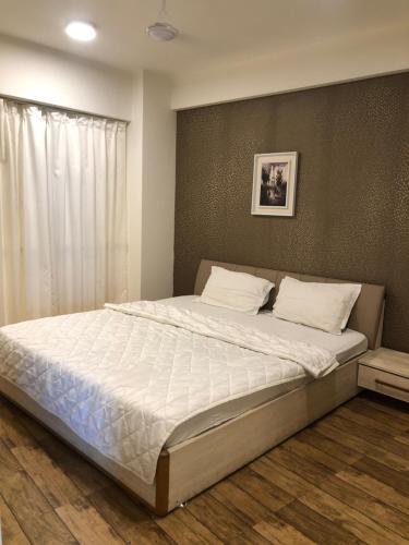 ein Schlafzimmer mit einem großen Bett mit weißer Bettwäsche in der Unterkunft Rajhans belliza 2bhk Flats in Surat