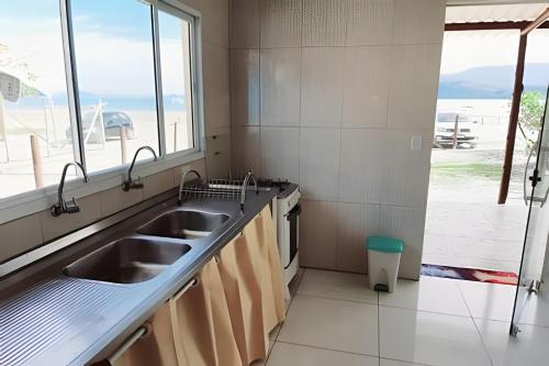 a kitchen with two sinks and a large window at Frente ao mar casa 42 Praia do Estaleiro in Ubatuba