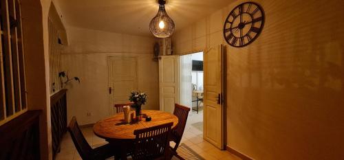 a dining room table with chairs and a clock on the wall at Le Madina in Pamandzi