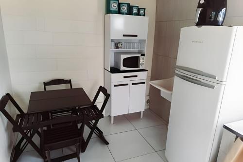 a small kitchen with a table and a white refrigerator at Frente ao mar casa 42 Praia do Estaleiro in Ubatuba
