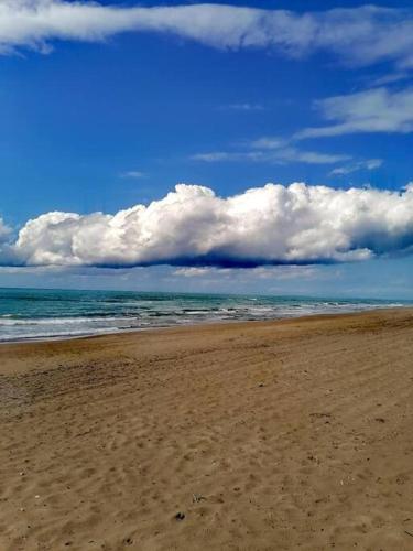 una playa de arena con el océano y nubes en el cielo en Studio Rodies in Neohori Zacharo, 