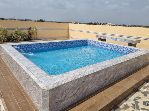 einen großen Pool mit einer Steinmauer in der Unterkunft Résidence Schilo - appartement équipé avec piscine privée et rooftop in Abomey-Calavi