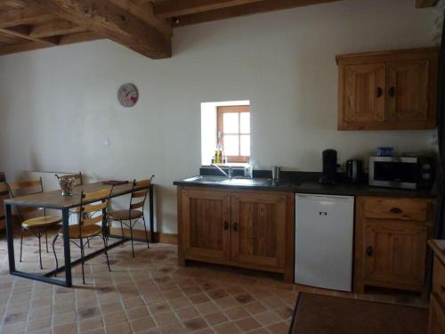 a kitchen with wooden cabinets and a table with chairs at Le Cercotin in Moroges