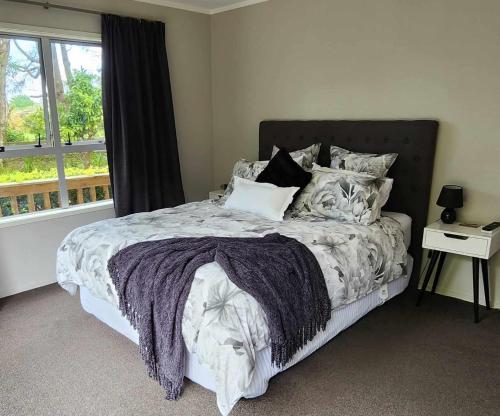 a bedroom with a large bed with a window at Woodbury Farm B&B in Takanini