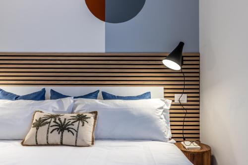 1 dormitorio con cama blanca y cabecero de madera en StayEasy Quadronno33 - 3 bedrooms, 2 baths - Duomo walking distance, en Milán