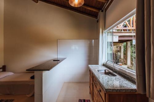 uma casa de banho com um lavatório e uma janela ao lado de uma cama em Chales do Ademir em Ilhabela