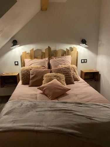 une chambre avec un grand lit avec des oreillers dessus dans l'établissement Als AS DE COEUR La maison aux mille et un coeurs, à Neuve-Église