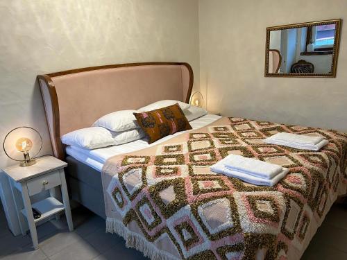 a bedroom with a bed with a blanket and a mirror at Halmstad Gårdshotell in Halmstad