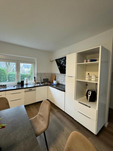 a kitchen with white cabinets and a table and chairs at Haus mit Garten - Kingbett - WIFI - Parkplatz in Essen
