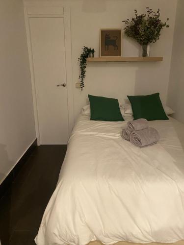 1 cama blanca grande con 2 almohadas verdes en Corrala en el Madrid histórico, en Madrid