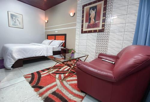 - une chambre avec un lit et un fauteuil en cuir rouge dans l'établissement Double twins Hotel & appartement, à Yaoundé