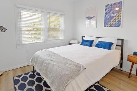 una camera da letto con un grande letto bianco con cuscini blu di Hot Tub Home By The Bay - 4BD 2BA ad Atlantic City