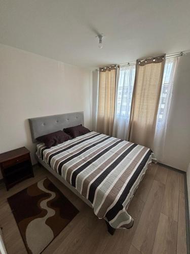 a bedroom with a bed with a striped blanket at Acogedor departamento arica in Arica