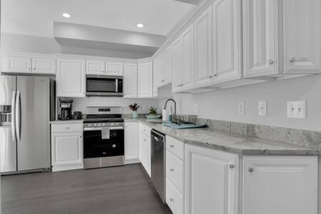a white kitchen with white cabinets and appliances at Bartram Dream House I - Bartram Beach Retreat in Atlantic City