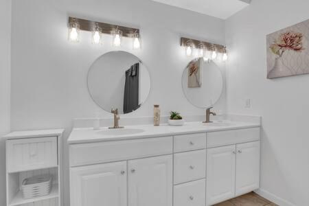 a white bathroom with two sinks and two mirrors at Bartram Dream House I - Bartram Beach Retreat in Atlantic City