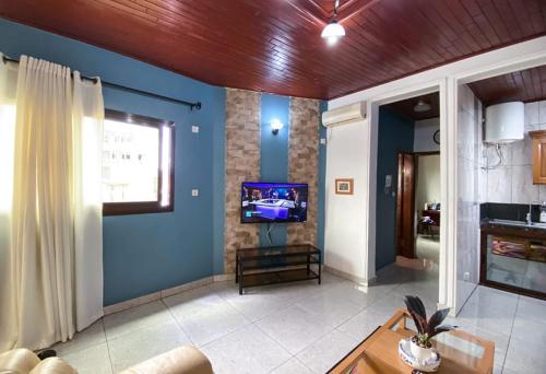 sala de estar con paredes azules y TV en Double twins Hotel & appartement, en Yaoundé