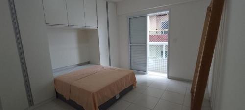 een slaapkamer met een bed in een kamer met een raam bij Apartamento Encantador in Praia Grande