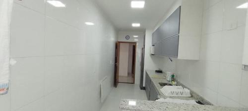 een witte badkamer met een wastafel en een aanrecht bij Apartamento Encantador in Praia Grande