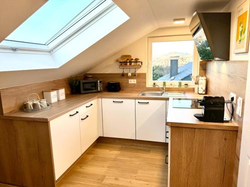 a kitchen with white cabinets and a skylight at Schwarzwaldliebe Ferienwohnung mit eigenem Garten in Gaggenau