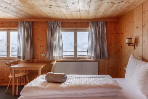 Schlafzimmer mit einem Bett, einem Tisch und Fenstern in der Unterkunft Ferienhaus Erath in Damüls