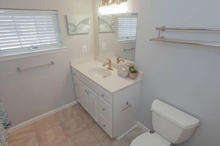 Baño blanco con aseo y lavamanos en Bartram Dream House II - Bartram Beach Retreat en Atlantic City