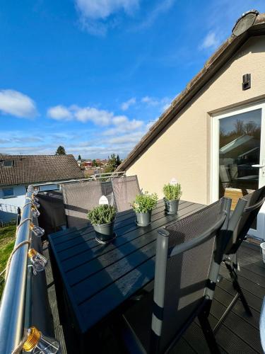 a table on a balcony with potted plants on it at Schwarzwaldliebe Ferienwohnung mit eigenem Garten in Gaggenau