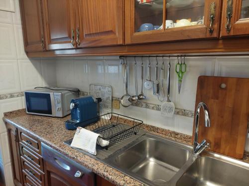 a kitchen counter with a sink and a microwave at Judith House - Amadora Este in Amadora