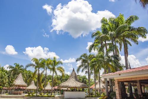 un complejo con palmeras y sombrillas en HOTEL CAMPESTRE Palma en Villavicencio
