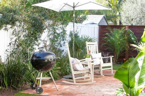 a grill and chairs and an umbrella in a garden at Adorable Octopus Hideaway: 2 min walk to the beach in Del Mar