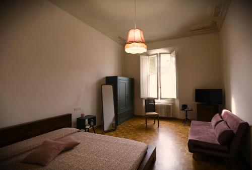 1 dormitorio con 2 camas, sofá y ventana en Belle Epoque, en Faenza
