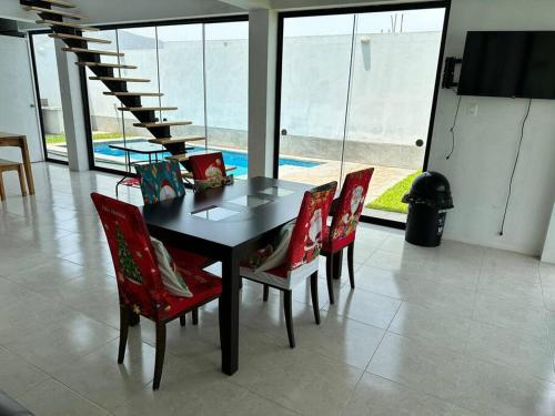 a dining room table with red chairs and a staircase at Casa de Campo Paz y Bien - Cieneguilla in Cieneguilla