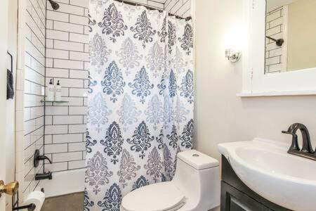 a bathroom with a toilet and a sink and a shower curtain at Luxe Bartram Beach Retreat 4BD - 3BA in Atlantic City