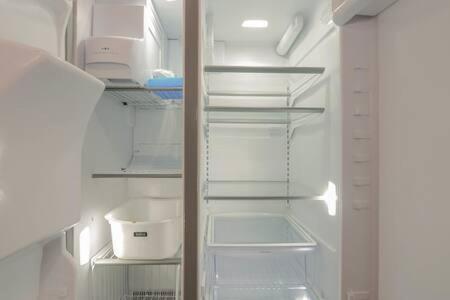 a refrigerator with its door open with its shelves at Escape to Raleigh Ave Glamour - Steps to the Beach in Atlantic City