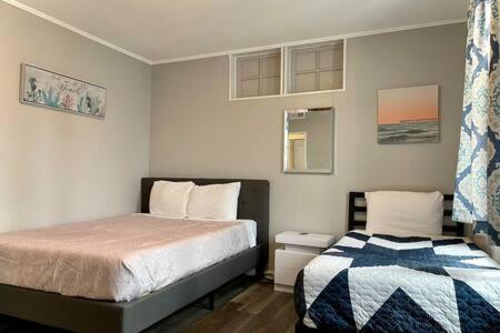 een slaapkamer met 2 bedden en een raam bij Escape to Raleigh Ave Glamour - Steps to the Beach in Atlantic City