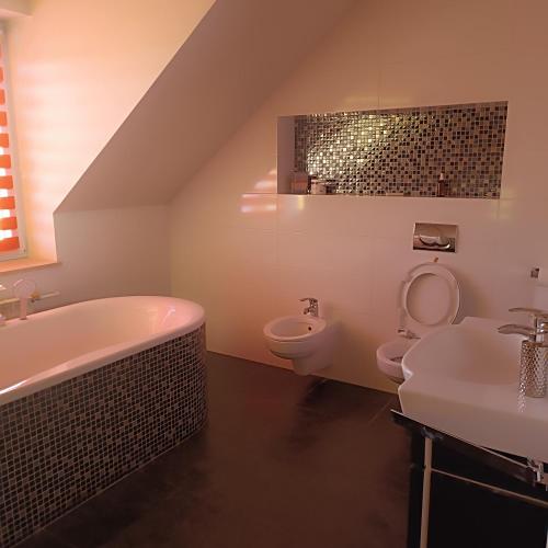 La salle de bains est pourvue d'un lavabo, d'une baignoire et de toilettes. dans l'établissement Noclegi w Bilczy 5 km do Kielc, à Bilcza