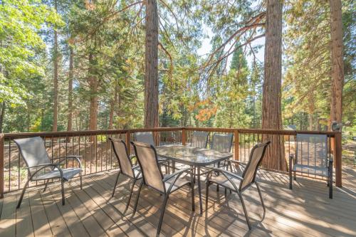 a table and chairs on a deck with trees at Peaceful Pinecone in Dorrington