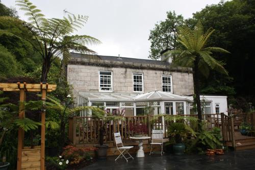 a garden with chairs and a greenhouse in front of a building at The Waterwheel in St Austell