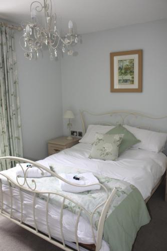 a bedroom with a white bed with a chandelier at The Waterwheel in St Austell