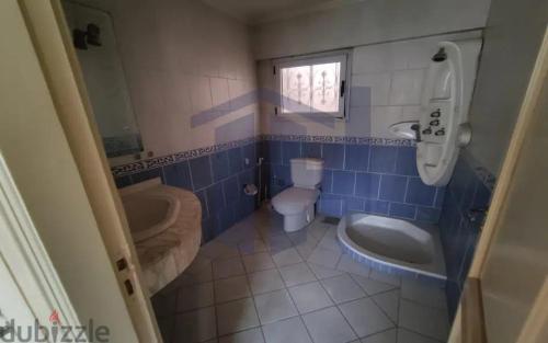 a blue tiled bathroom with a toilet and a sink at Manksha in Alexandria