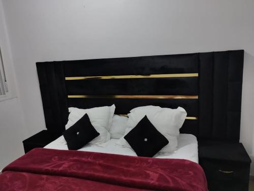a black and white bed with black pillows on it at Appartement du luxe in Ifrane