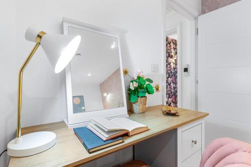 una scrivania con specchio, lampada e libri di Modern One Bedroom Flat - Near Heathrow, Windsor Castle, Thorpe Park - Staines London TW18 a Staines upon Thames