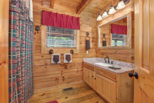 La salle de bains est pourvue d'un lavabo et d'un miroir. dans l'établissement Hook, Line and Sinker Cabin features firepit and hot tub!, à Sevierville