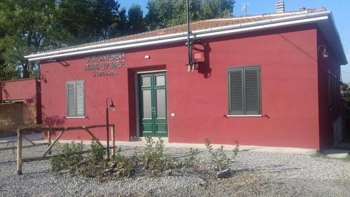 ein rotes Gebäude mit grüner Tür und Fenstern in der Unterkunft La Sanguigna B&B e Locanda in Castelnuovo della Misericordia