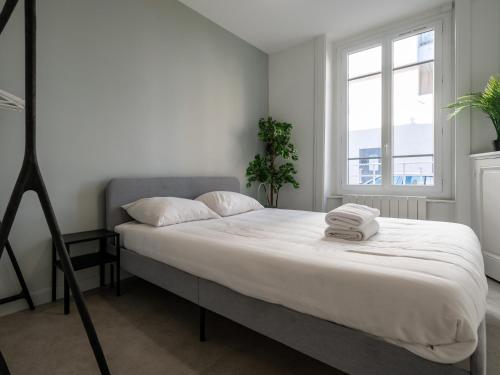 Schlafzimmer mit einem Bett mit weißer Bettwäsche und einem Fenster in der Unterkunft Le cocon urbain T3, 6 personnes, avec parking proche TRAM ET METRO in Villeurbanne