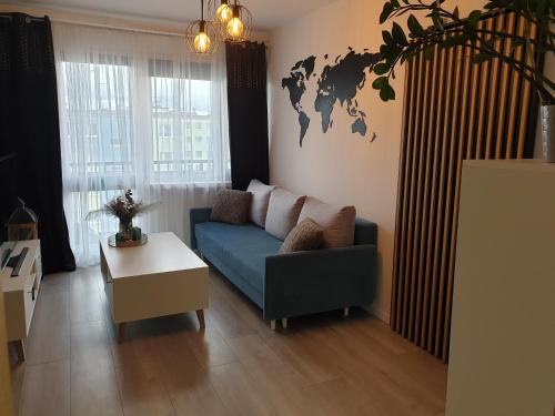 a living room with a blue couch and a world map on the wall at Apartament Kościuszki Iława in Iława