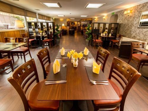 Tigh Na Mara Hotel في Sandhead: غرفة طعام مع طاولة وكراسي خشبية