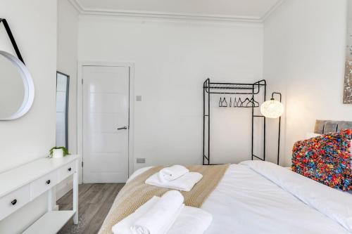 ein weißes Schlafzimmer mit einem Bett und einem Spiegel in der Unterkunft Relocators, Medical Staff, Families in Luton